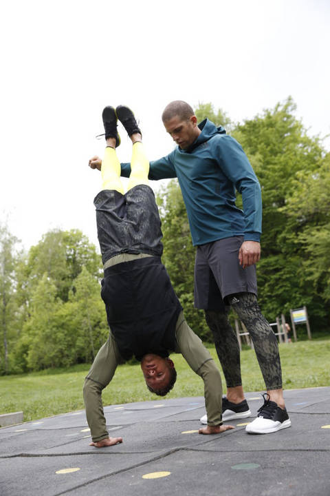 Ein Mann macht Handstand und der zweite Mann gibt Hilfestellung.