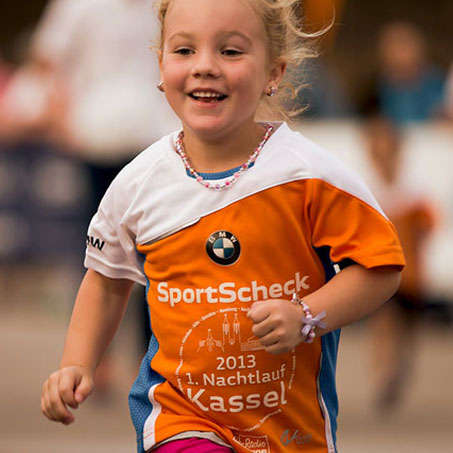 Ein junges Mädchen läuft lächelnd beim Stadtlauf Kassel für Kids mit.