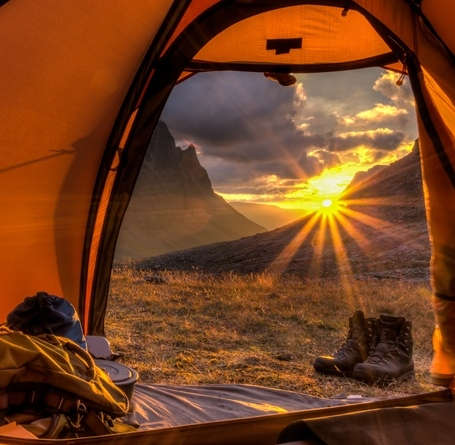 Ein Sonnenuntergang im Gebirge aus einem Zelt heraus fotografiert.