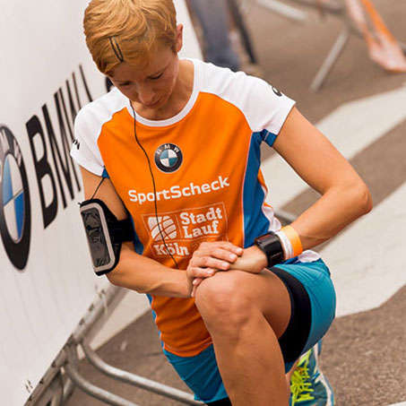 Eine Frau dehnt vor dem Start des Stadtlaufs in Köln ihre Beinmuskulatur.
