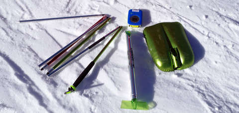 Ein Lawinenausrüstung-Set liegend im Schnee. Bestehend aus Schaufel, Sonde und LVS-Gerät.