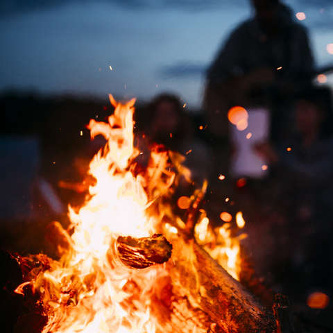 Ein Lagerfeuer brennt in der Nacht und wärmt Wanderer.