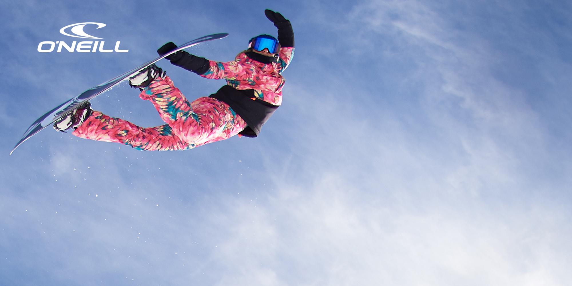 Eine Snowboarderin springt und macht dabei einen Nosegrab