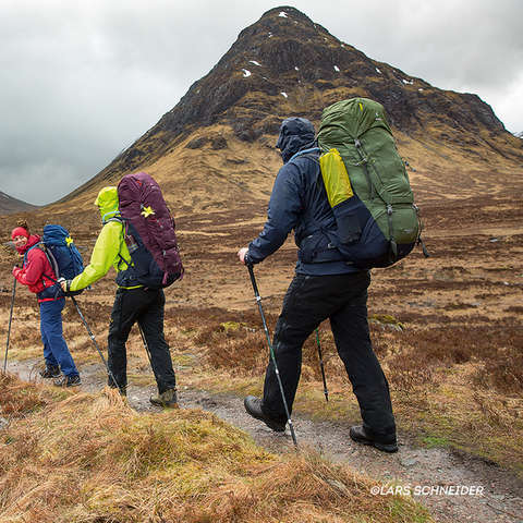 Eine Gruppe Wanderer läuft durch die schottischen Highlands während es bewölkt ist.