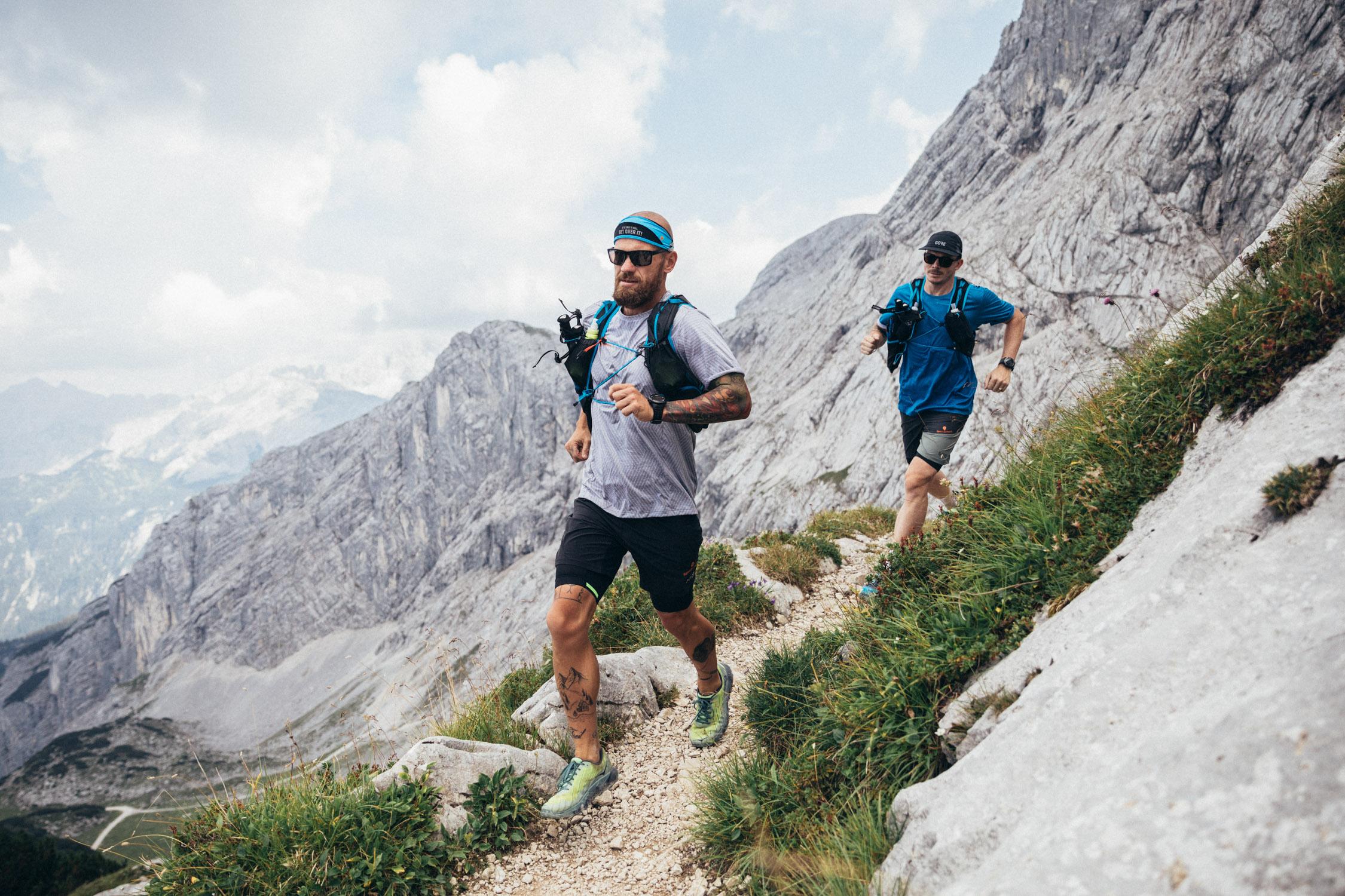 Zwei Trailrunner laufen durch eine alpine Natur