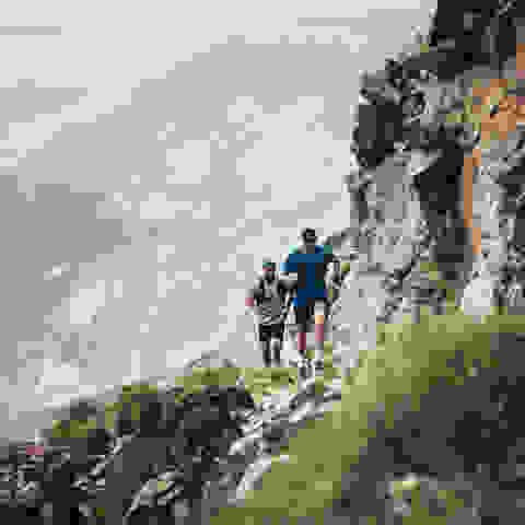 Zwei Trailrunner laufen einen Trail im Hochgebirge.