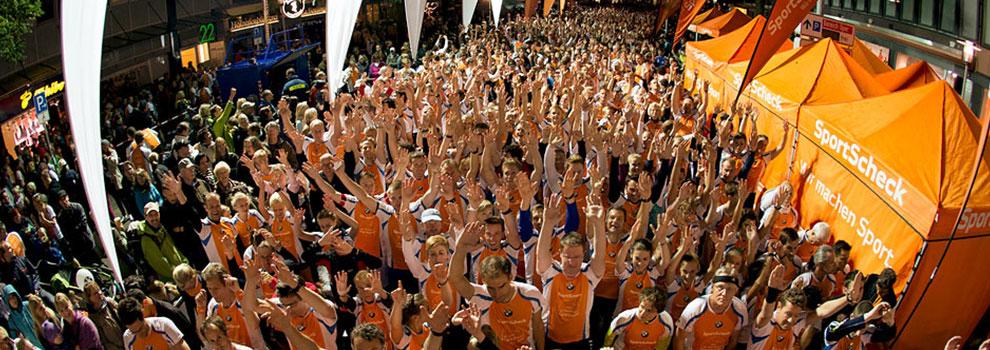 Viele Teilnehmer beim Hannover Nachtlauf strecken die Arme in die Luft und feiern.