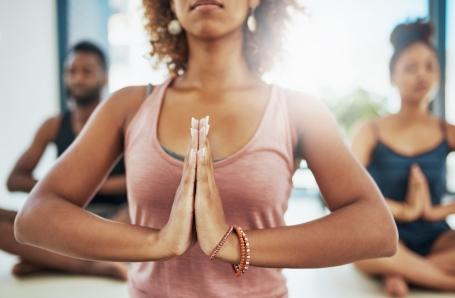 Eine Frau formt ihre Hände zur Yoga Begrüßung Namaste.