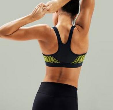 Eine Frau steht mit dem Rücken zur Kamera und hat die Arme über dem Kopf verschränkt. Sie trägt einen Nike Pro Classic Sport-BH. Eine Frau steht mit dem Rücken zur Kamera und hat die Arme über dem Kopf verschränkt. Sie trägt einen Nike Pro Classic Sport-BH.