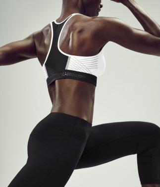 Eine Frau in der Seitenansicht. Sie trägt einen weißen Nike Pro Fierce Sport BH. Eine Frau in der Seitenansicht. Sie trägt einen weißen Nike Pro Fierce Sport BH.