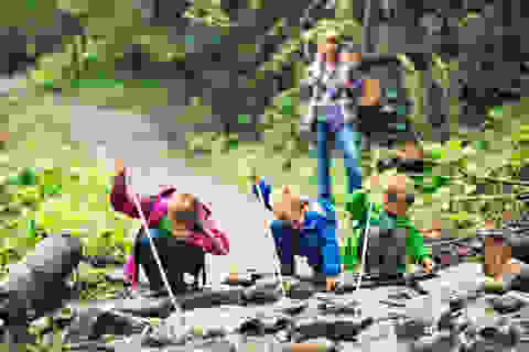 Eine Gruppe Kinder trinkt beim Wandern aus einem Bach