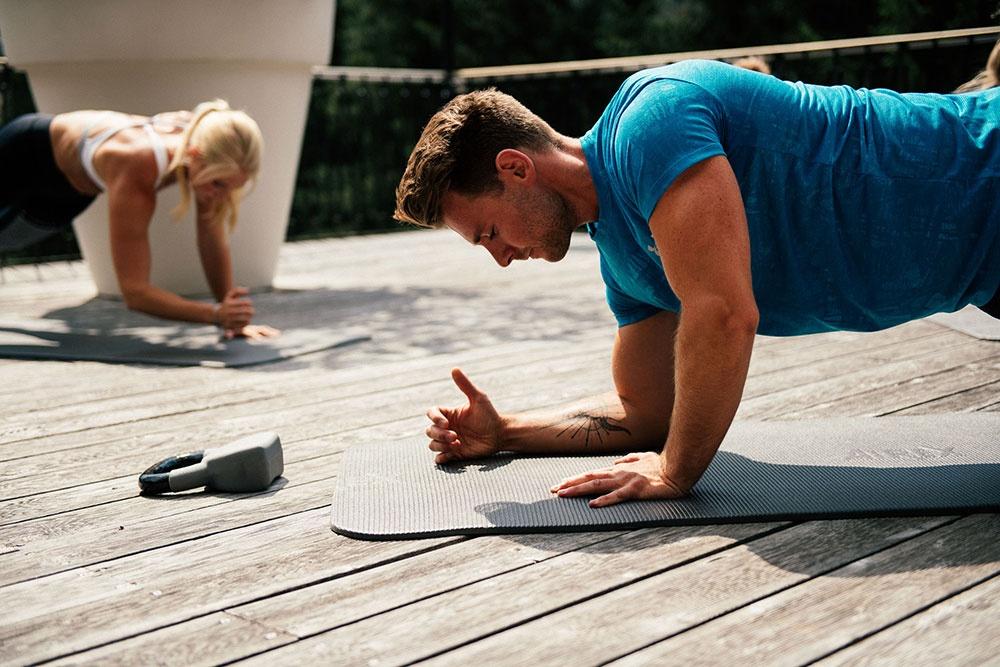 Ein Rucksack steht auf einer Wiese. Im Hintergrund ist ein Bergpanorama zu sehen.