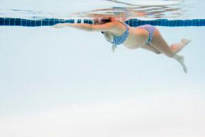 Eine schwangere Frau schwimmt in einem Schwimmbecken.