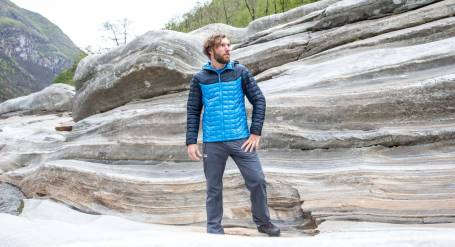 Ein Mann steht in einer Primaloft Jacke auf einem Felsen.
