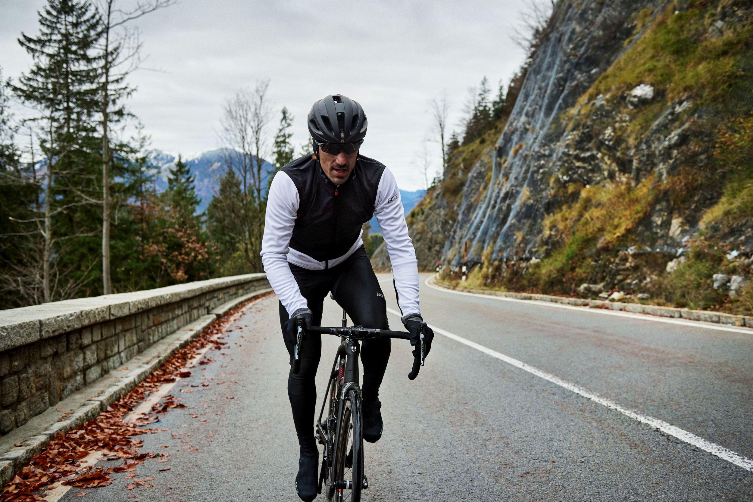 Ein Radfahrer f&auml;hrt auf einer Stra&szlig;e in einer herbstlichen Naturlandschaft