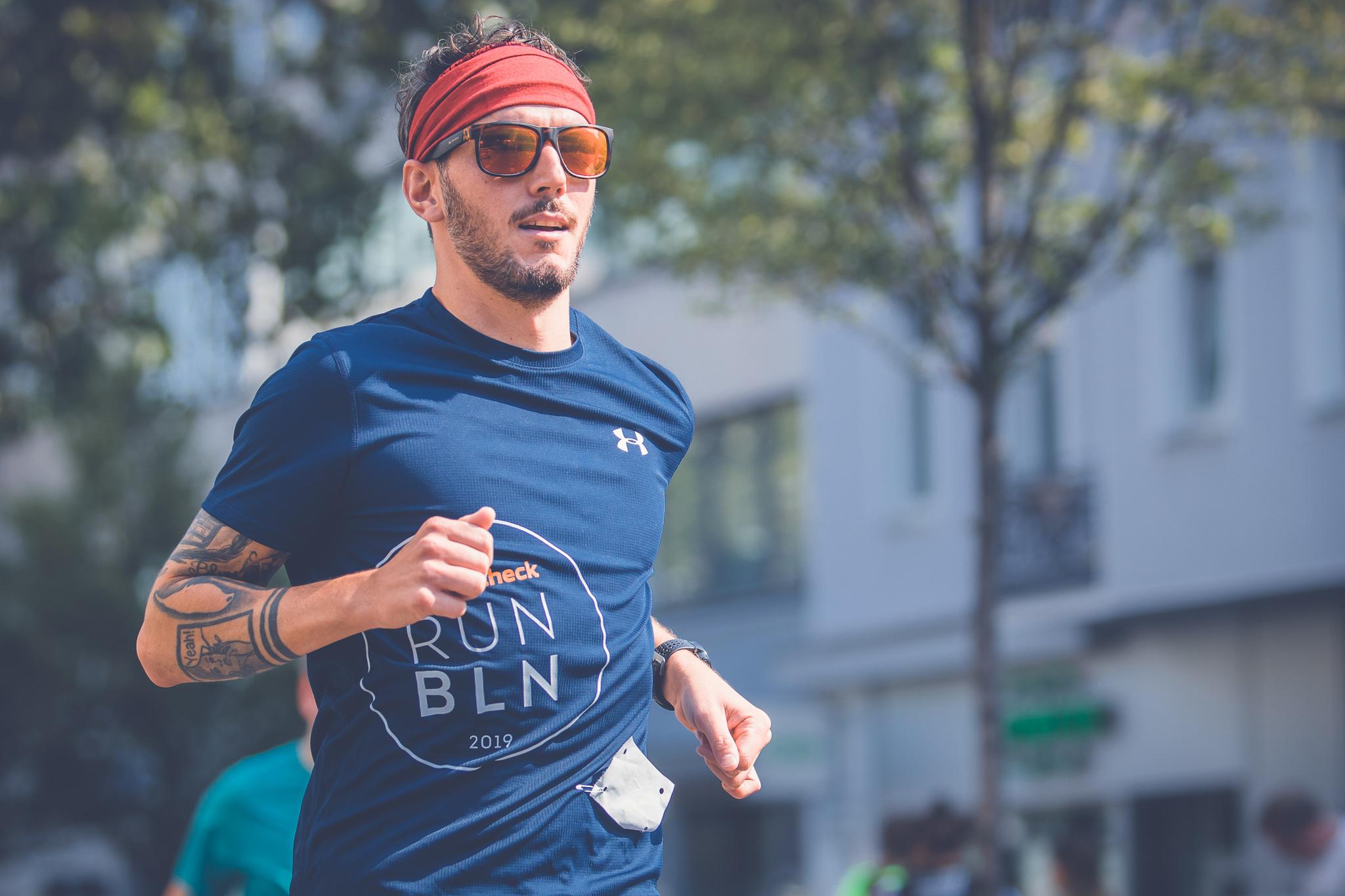 Ein Mann mit Stirnband und Sonnenbrille läuft durch die Stadt.