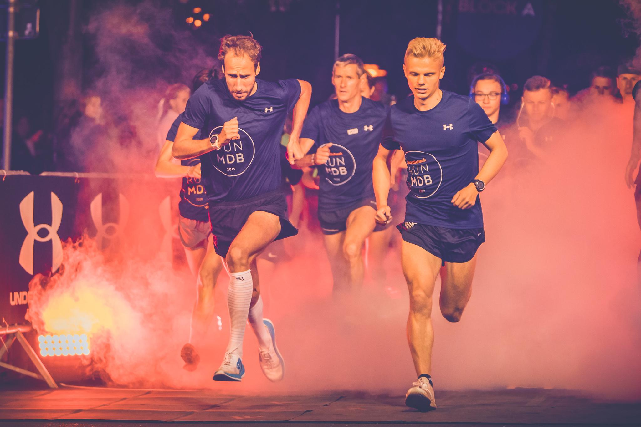 Drei Jogger laufen eine Stra&szlig;e entlang.