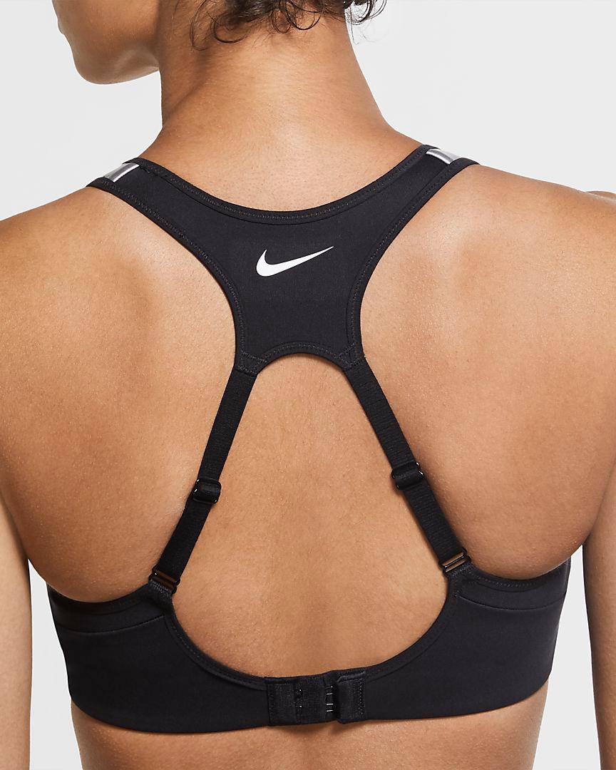 Eine Frau steht mit dem Rücken zur Kamera. Sie trägt einen schwarzen Nike Alpha Sport-BH mit starkem Halt.