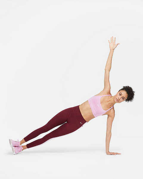 Eine Frau in einem Nike Indy Sport-BH in rosa mit leichtem Halt bei einer Yogaübung.