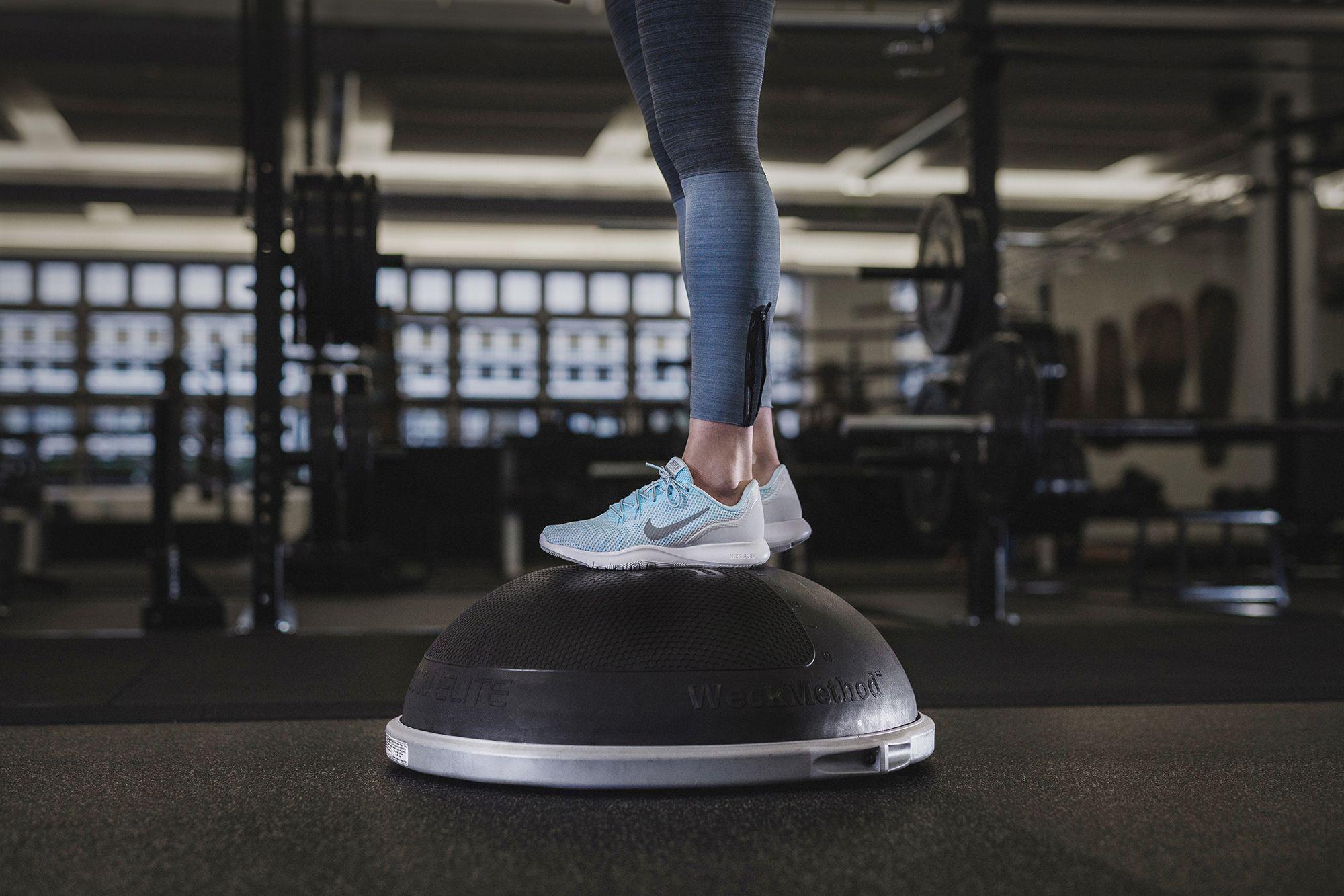 Eine Frau trainiert ihr Gleichgewicht auf einem Balance-Board.