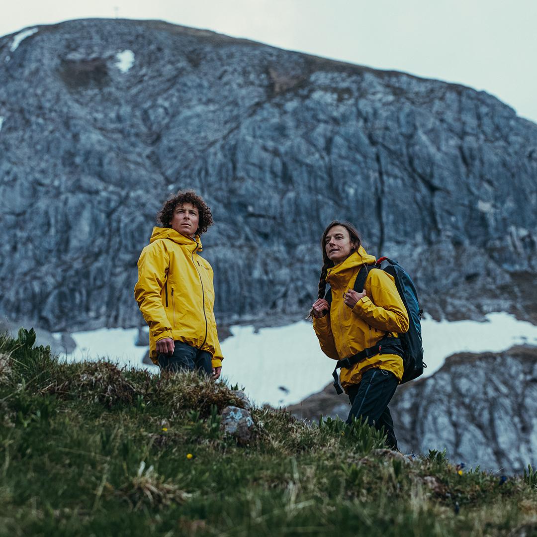 Mann und Frau tragen gelbe adidas Terrex Regenjacken in den Bergen.