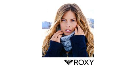 Eine blonde Frau mit Schal und Winterjacke in einer Winterlandschaft