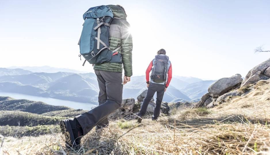 Zwei Personen wandern in einer sonnigen Berglandschaft