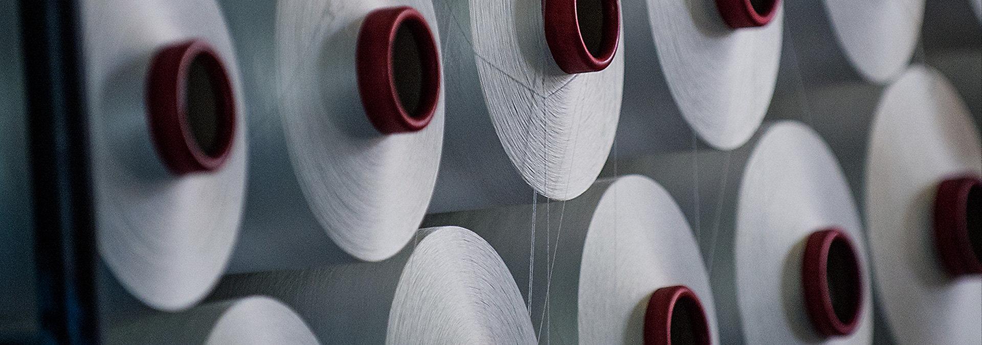 Reihen wei&szlig;er Garnspulen mit rotem Kern in einer Textilproduktion