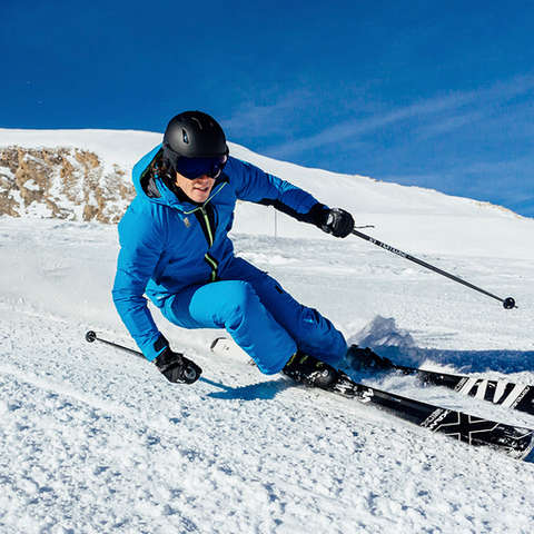 Ein Skifahrer fährt sehr schnell mit perfekter Technik eine Piste hinab.