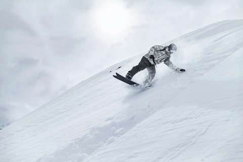 Ein Snowboarder fährt eine Pulverschnee-Piste hinab.