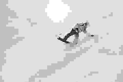 Ein Snowboarder fährt eine Pulverschnee-Piste hinab.