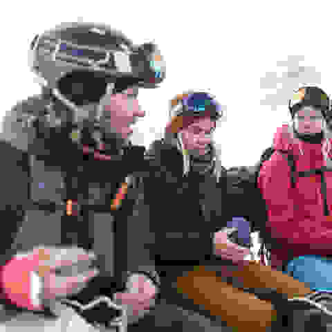 Eine Gruppe Snowboarder sitzt in der Kabine einer Gondel.