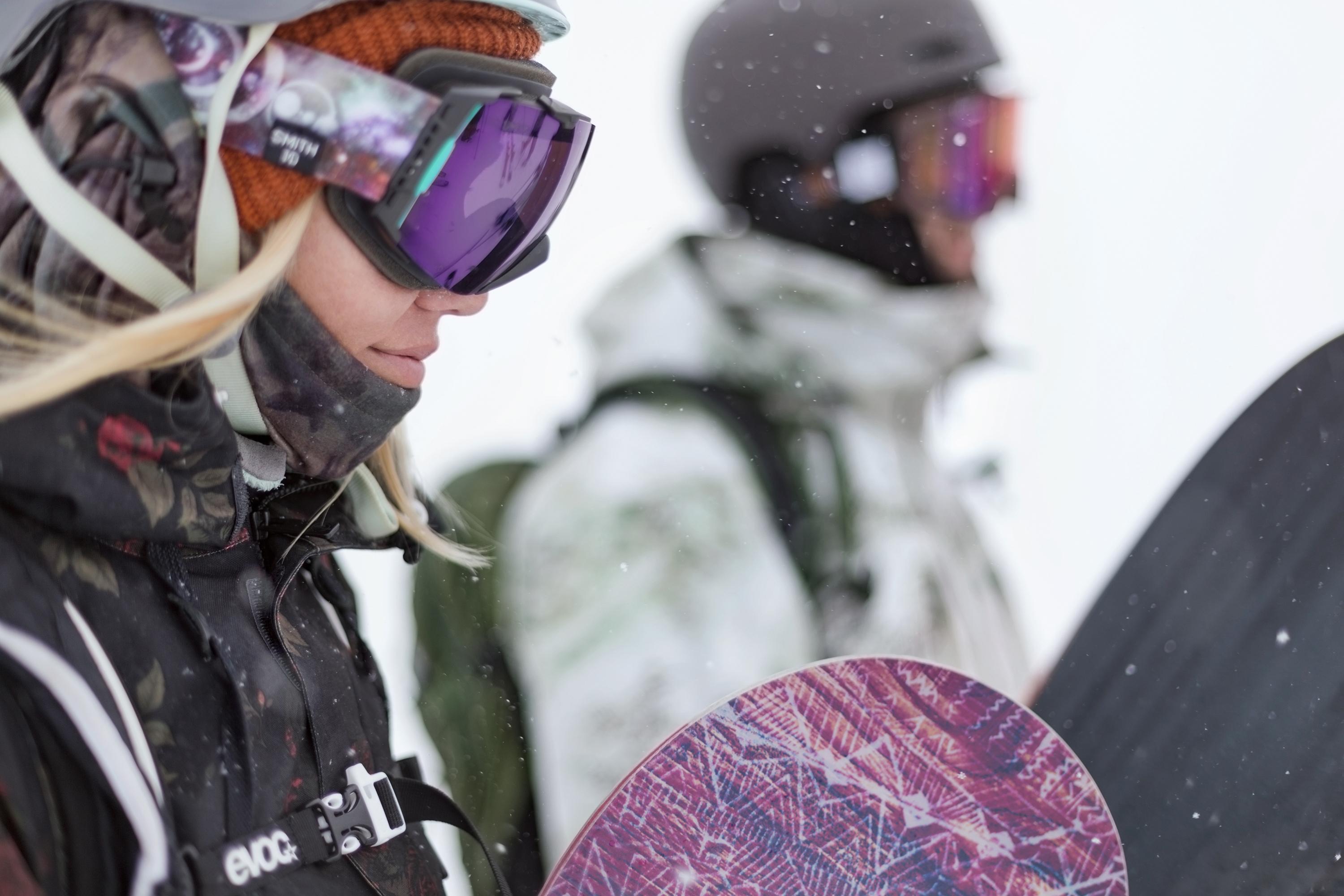 Ein Snowboarder und eine Snowboarderin machen sich an einem verschneiten Tag zur Abfahrt bereit