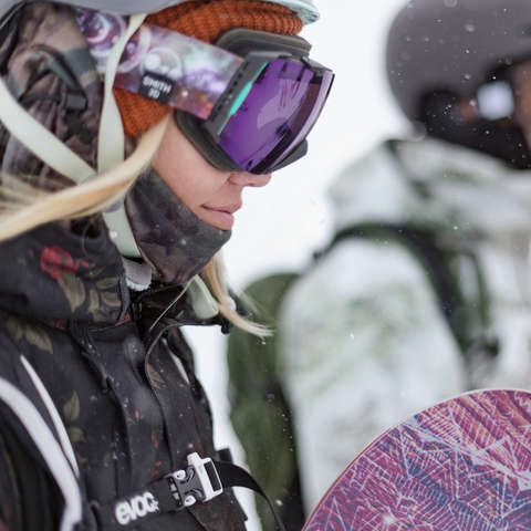 Ein Snowboarder und eine Snowboarderin machen sich an einem verschneiten Tag zur Abfahrt bereit