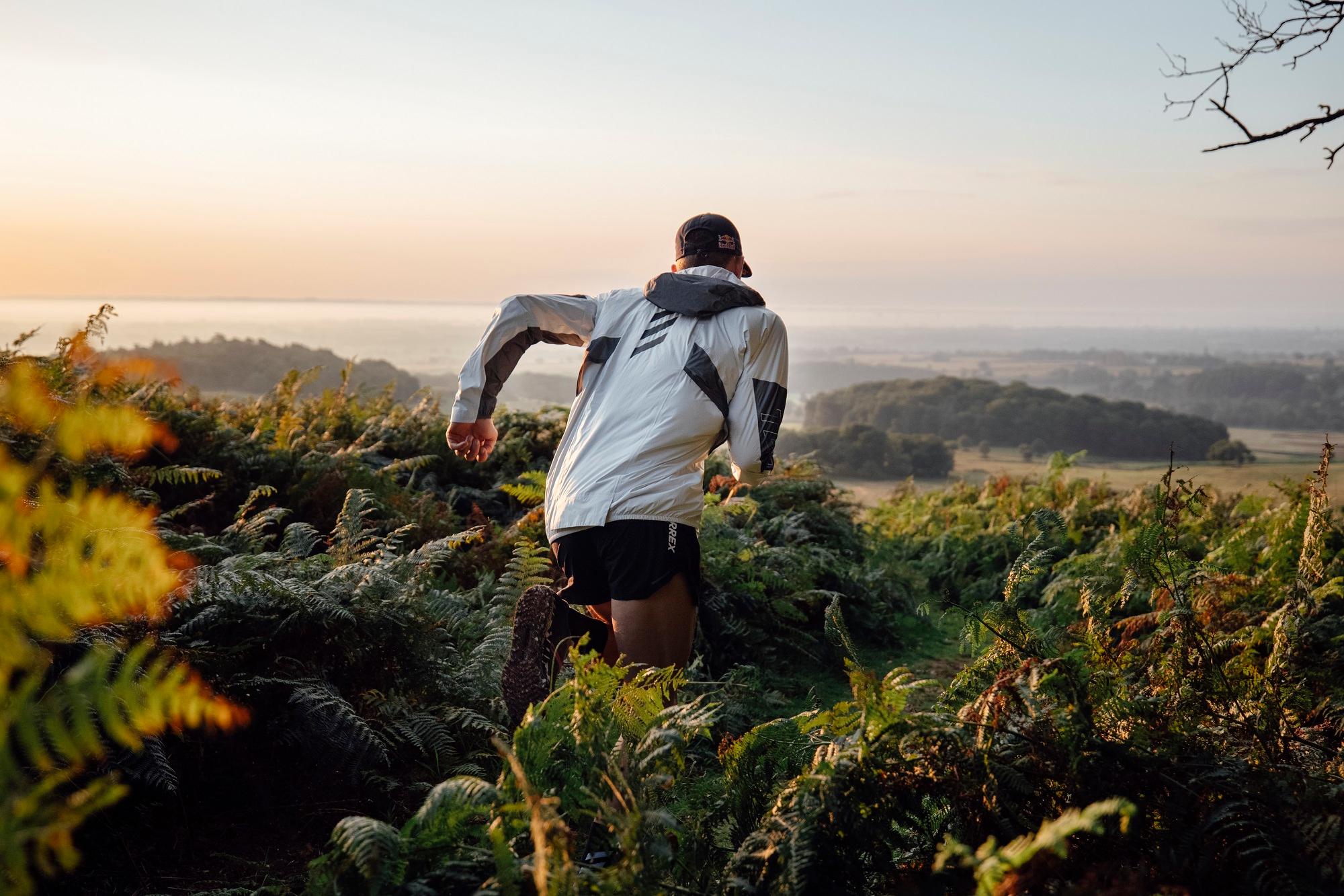 Mann mit adidas Jacke läuft dynamisch über felsiges Gelände