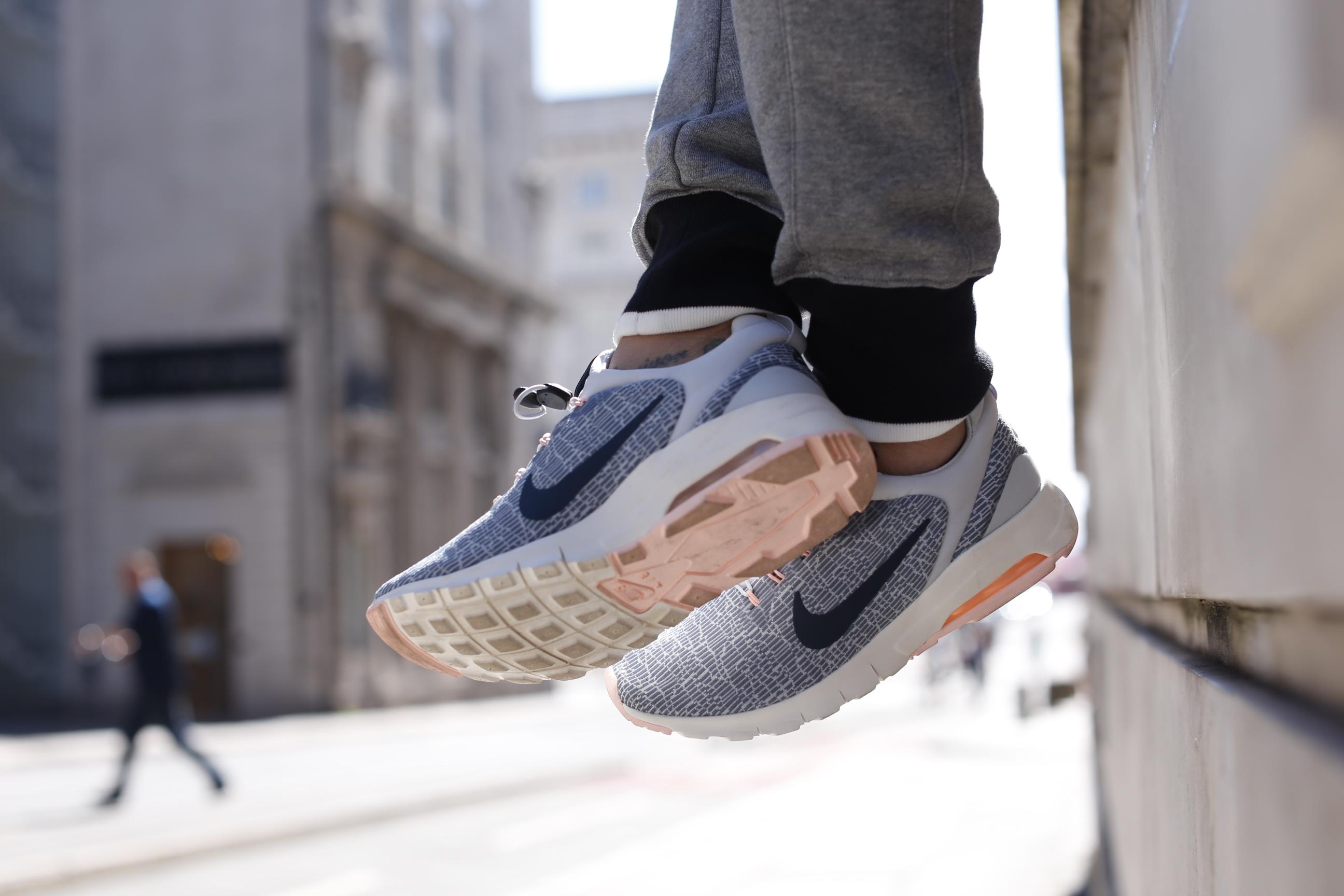 Eine Person trägt grau-weiße Nike-Sportschuhe