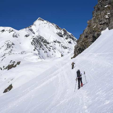 Zwei Schneeschuhwanderer wenden spezielle Steigtechnik in steilem Gelände an.
