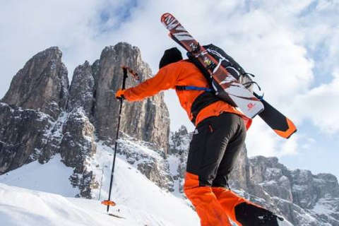 Ein Skitourer fährt bergauf und hat einen Rucksack voll nützlicher Ausrüstung auf dem Rücken.