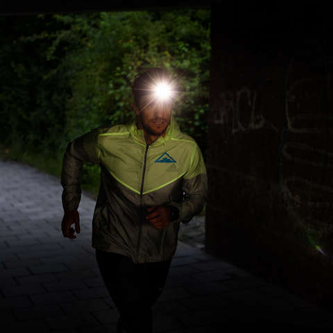 Ein Mann läuft bei Dunkelheit mit einer Stirnlampe.