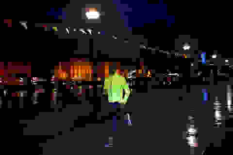Ein Mann läuft bei Dunkelheit mit neongelb reflektierender Jacke.