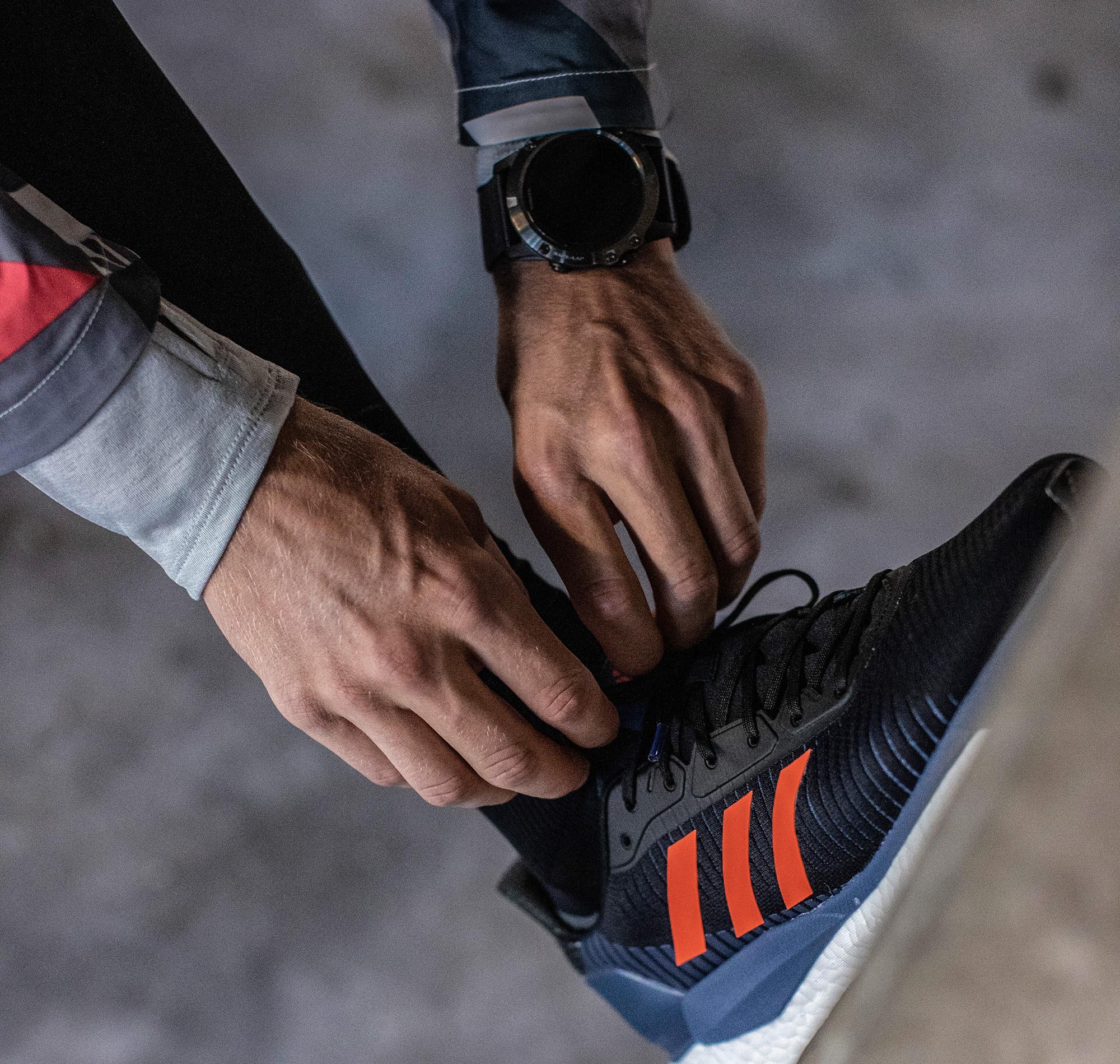 Ein Läufer überprüft mit seiner Laufuhr die Herzfrequenz bei der Halbmarathon Vorbereitung.