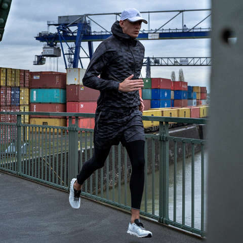 Ein Läufer läuft bei Regen mit einer Cap über eine Brücke.