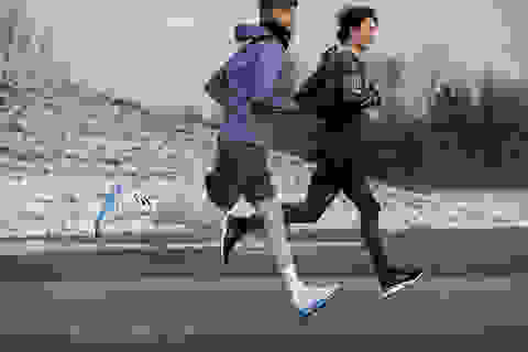 Zwei Joggern laufen bei kälteren Temperaturen eine Straße entlang.