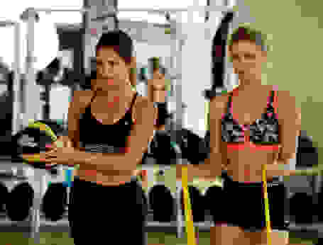 2 Frauen trainieren im Fitnessstudio in Sport-BHs. 