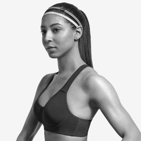 Eine Frau steht seitlich zur Kamera und trägt einen schwarzen Sport BH von Nike. Eine Frau steht seitlich zur Kamera und trägt einen schwarzen Sport BH von Nike.