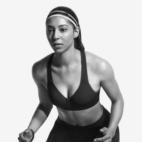Eine Frau steht leicht vorgebeugt und trägt dabei einen schwarzen Nike Sport-BH.