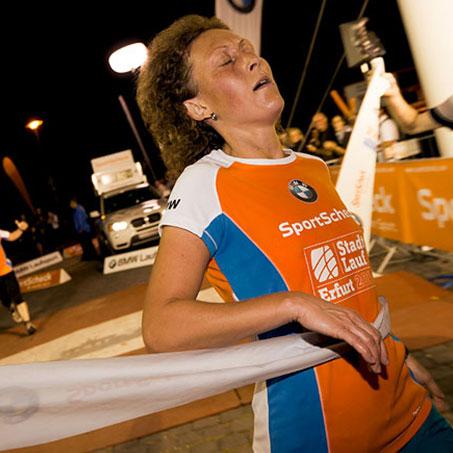 Eine Läuferin kommt erschöpft und erleichtert im Ziel beim Stadtlauf Erfurt an.