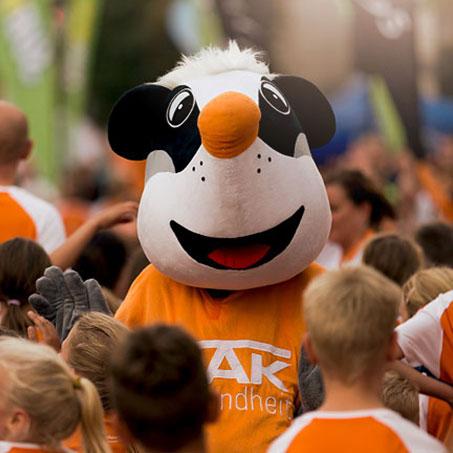 Das Maskottchen der DAK umringt von Kindern beim Stadtlauf Magdeburg.