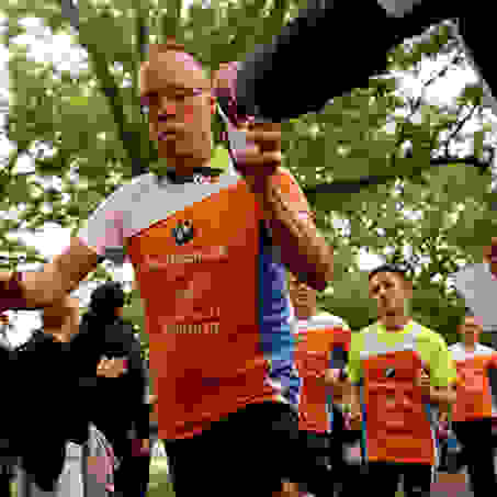 Ein Läufer bekommt während des Laufens beim Stadtlauf Hamburg einen Becher mit Wasser gereicht.