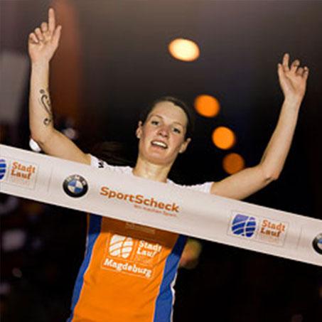 Eine Läuferin mit hochgerissenen Armen kurz vor dem Zieleinlauf beim Stadtlauf Magdeburg.